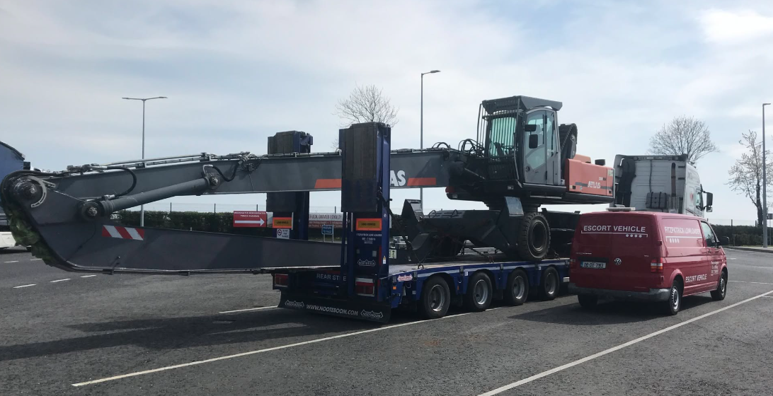 Fitzpatrick low loader carrying an Atlas material handler with escort van